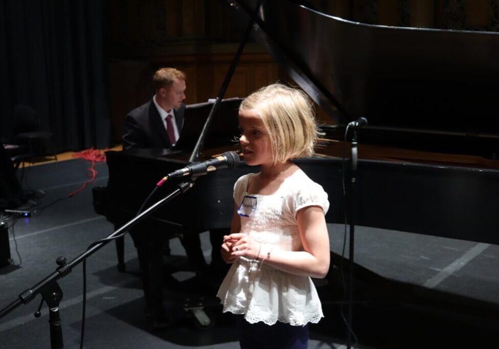 blonde kid singing on stage
